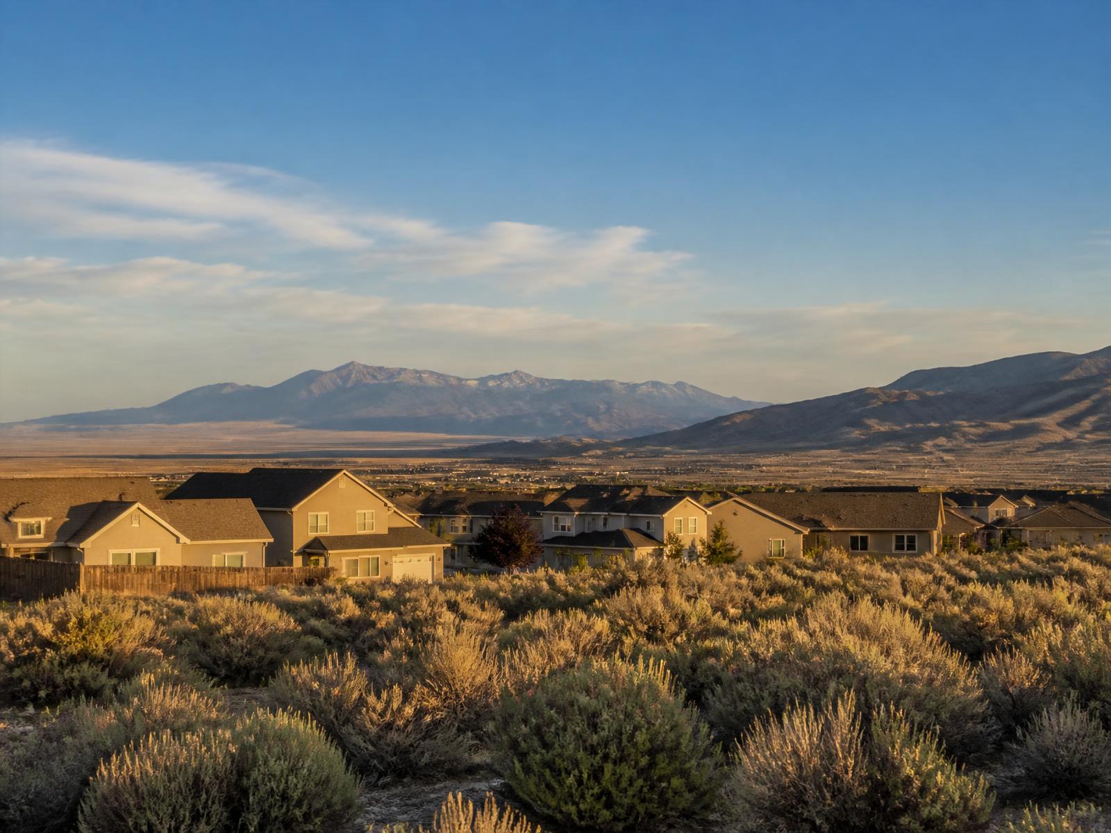 Sagebrush and homes at the edge of Fernley, Nevada, with distant mountains at golden hour